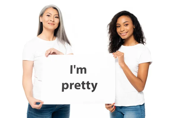 Glücklich afrikanisch-amerikanische und asiatische Frauen halten ich bin ziemlich Plakat isoliert auf weiß — Stockfoto