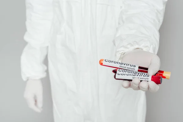 Visão parcial do epidemiologista de fato de treino mostrando tubos de ensaio com amostras de sangue sobre fundo cinzento — Fotografia de Stock