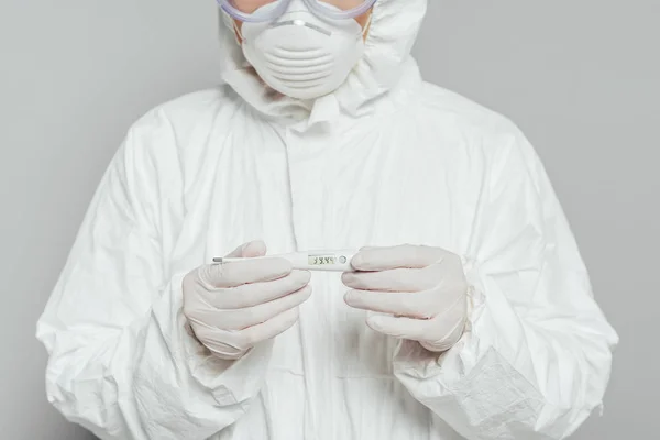 Vista recortada del epidemiólogo que sostiene el termómetro que muestra alta temperatura aislada en gris - foto de stock