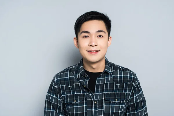 Young asian man looking at camera and smiling on grey background — Stock Photo