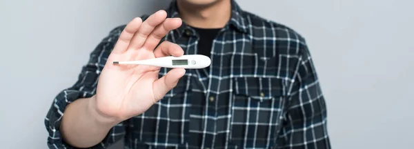 Cropped view of man holding thermometer showing high temperature isolated on grey, panoramic shot — Stock Photo