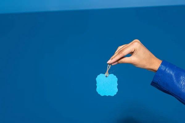 Vista recortada de mujer afroamericana sosteniendo etiqueta en blanco sobre fondo azul - foto de stock