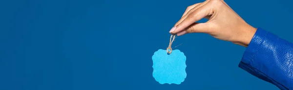 Cropped view of african american woman holding blank label isolated on blue, panoramic shot — Stock Photo