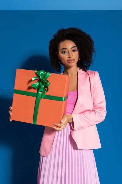 Elegante donna afroamericana con regalo su sfondo blu — Foto stock