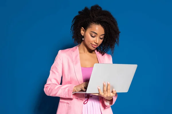 Элегантный африканский американский бизнесмен с помощью ноутбука на синем фоне — стоковое фото