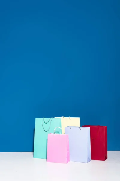 Sacos de compras de papel coloridos no fundo azul — Fotografia de Stock