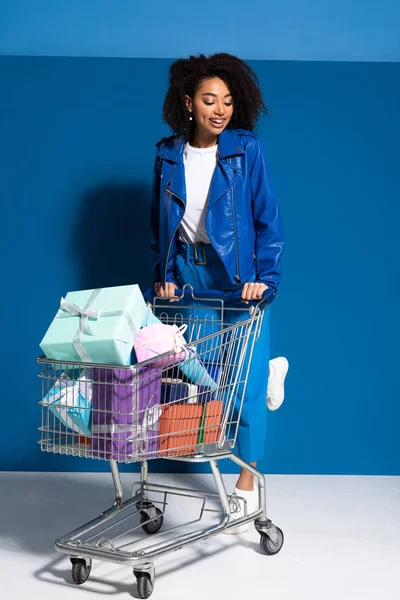 Улыбающаяся африканская американка с корзиной с подарками на синем фоне — стоковое фото