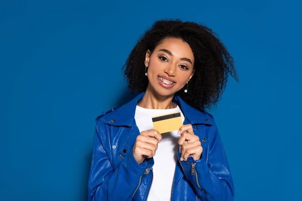 Mulher americana africana feliz com cartão de crédito no fundo azul — Fotografia de Stock
