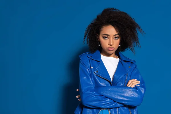 Femme afro-américaine grave avec les bras croisés sur fond bleu — Photo de stock