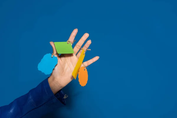 Vista recortada de mujer afroamericana con etiquetas vacías en la mano sobre fondo azul - foto de stock