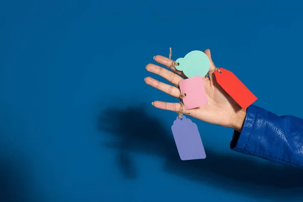 Cropped view of african american woman with empty labels on hand on blue background — Stock Photo