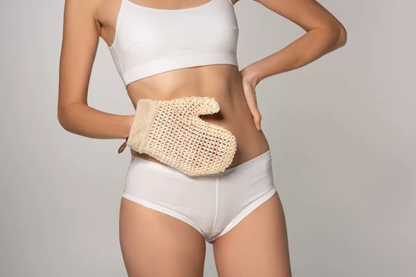 Cropped view of slim girl with perfect skin holding scrub glove, isolated on grey — Stock Photo