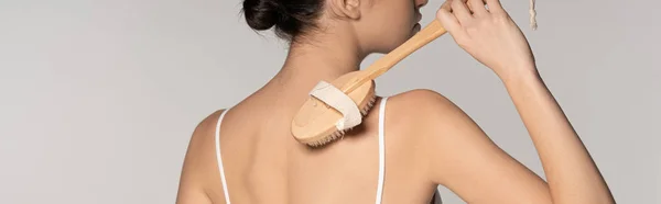 Tiro panorâmico da mulher usando escova de massagem, isolado em cinza — Fotografia de Stock