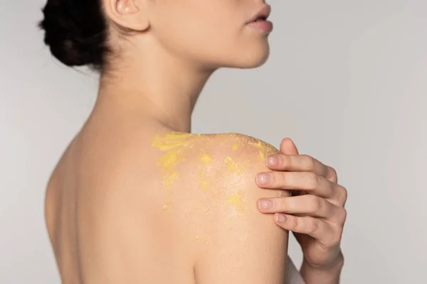 Vista parziale di ragazza che applica scrub agli agrumi sale sulla spalla, isolato su grigio — Foto stock