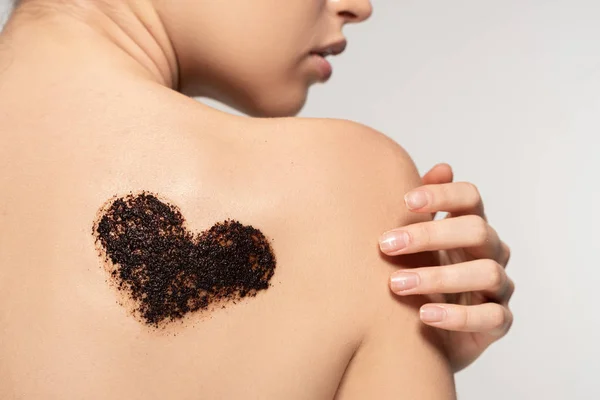 Partial view of girl with heart sign of coffee scrub on body, isolated on grey — Stock Photo