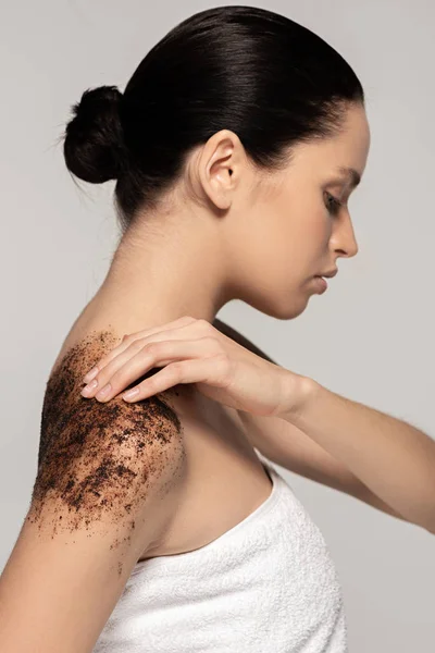 Beautiful girl applying coffee scrub on shoulders, isolated on grey — Stock Photo