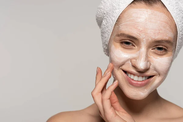 Atractiva chica alegre aplicando máscara cosmética en la cara, aislado en gris - foto de stock