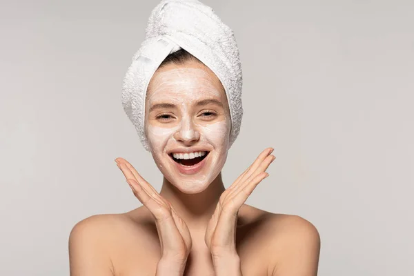 Excited woman with cosmetic mask on face and towel on head, isolated on grey — Stock Photo