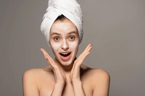 Menina animado com máscara cosmética no rosto e toalha na cabeça, isolado em cinza — Fotografia de Stock