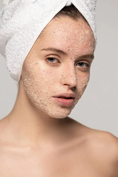 Bela mulher com esfoliação de coco no rosto e toalha na cabeça, isolado em cinza — Fotografia de Stock