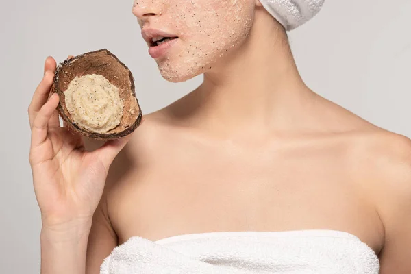 Vista ritagliata di ragazza con asciugamano sulla testa tenuta guscio di cocco con scrub, isolato su grigio — Foto stock