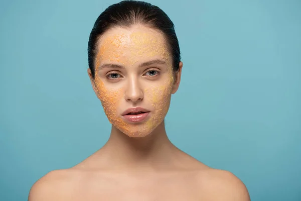 Schöne Mädchen Anwendung gelben Zucker Peeling auf Gesicht, isoliert auf blau — Stockfoto