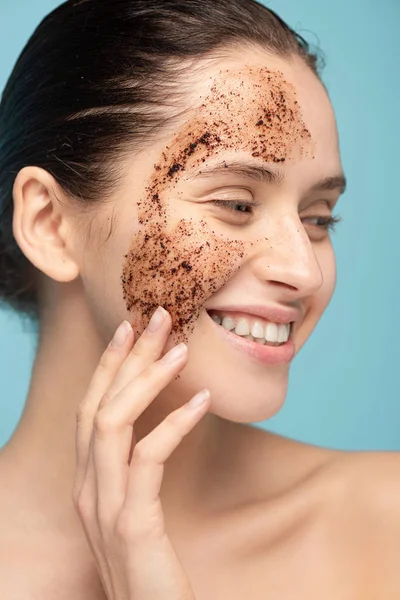 Glücklich schöne Frau Anwendung Kaffee Peeling auf Gesicht, isoliert auf blau — Stockfoto