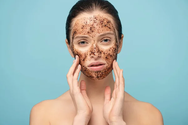 Beautiful girl applying coffee scrub on face, isolated on blue — Stock Photo