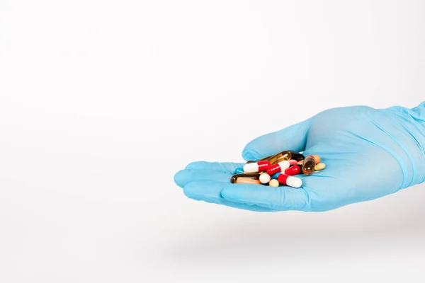 Wissenschaftler in blauem Latex-Handschuh mit Pillen auf weißem Grund — Stockfoto