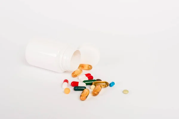 Bottle near colorful pills on white with copy space — Stock Photo