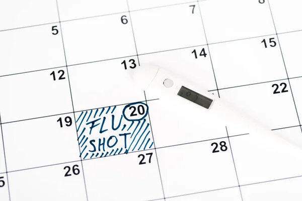 Termómetro digital en el calendario con fecha marcada y letras de inyección de gripe — Stock Photo