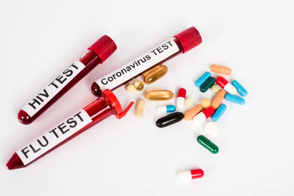 Pilules colorées près des échantillons avec lettrage sur blanc — Photo de stock