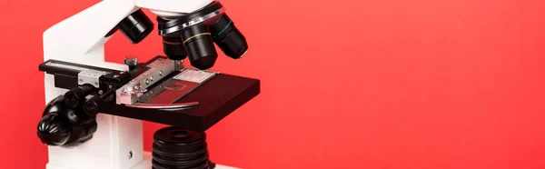 Panoramic shot of microscope with sample on glass isolated on red — Stock Photo