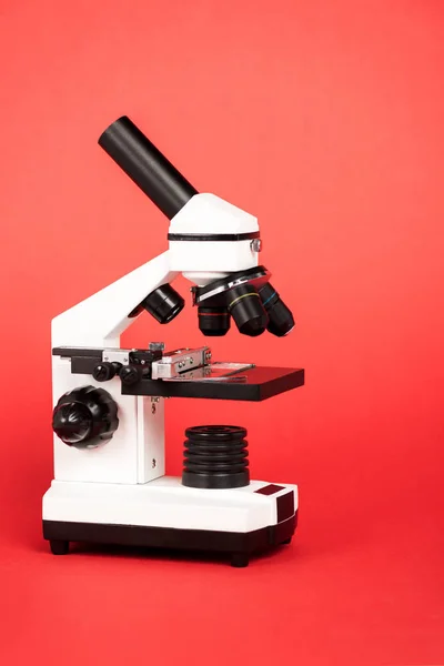 Modern microscope with sample on red — Stock Photo