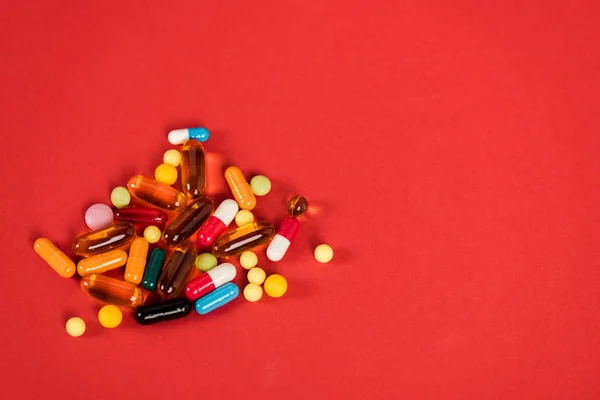 Colorful pills on red with copy space — Stock Photo