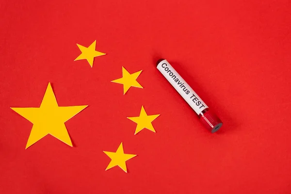 Vista dall'alto del campione con scritta coronavirus vicino alla bandiera cinese rossa — Foto stock