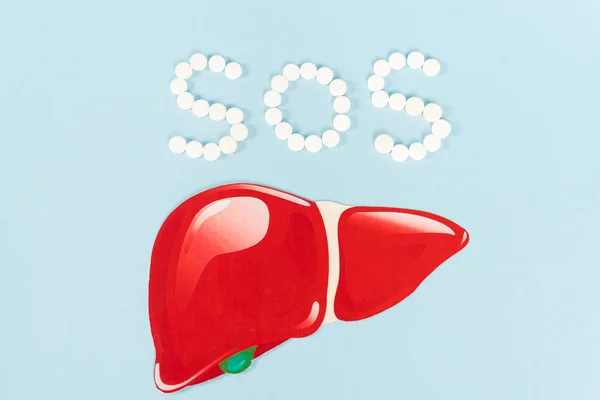 Top view of sos lettering near drawn liver on blue — Stock Photo