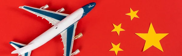 Panoramic shot of toy airplane on red chinese flag — Stock Photo