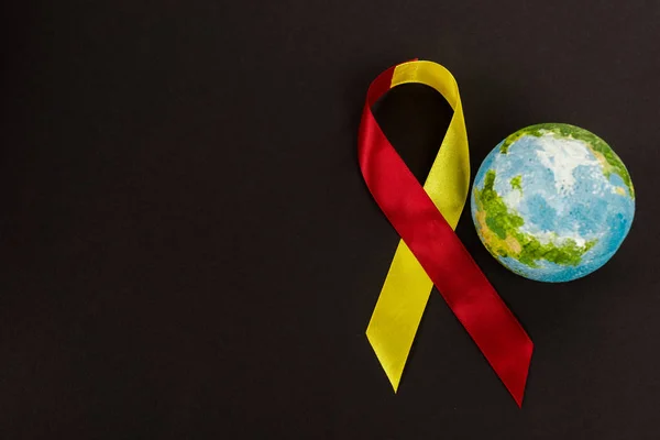 Вид зверху на земну кулю поблизу червоної та жовтої стрічки як усвідомлення гепатиту c ізольовано на чорному — стокове фото