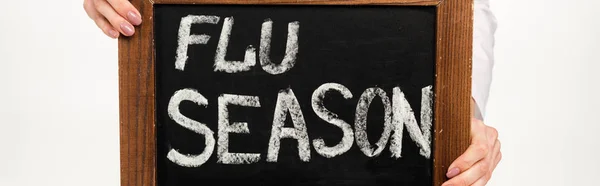 Inyección panorámica de médico sosteniendo pizarra con letras de la temporada de gripe aislado en blanco - foto de stock
