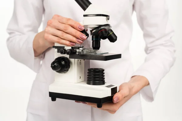 Vista ritagliata dello scienziato in mantello bianco con microscopio isolato su bianco — Foto stock