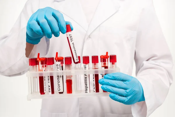 Vista recortada del científico en guantes de látex azul sosteniendo la muestra con letras de prueba de coronavirus aisladas en blanco - foto de stock