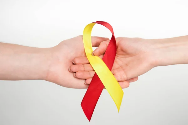 Vista recortada del hombre y la mujer sosteniendo cinta roja y amarilla como la hepatitis c conciencia aislada en blanco - foto de stock
