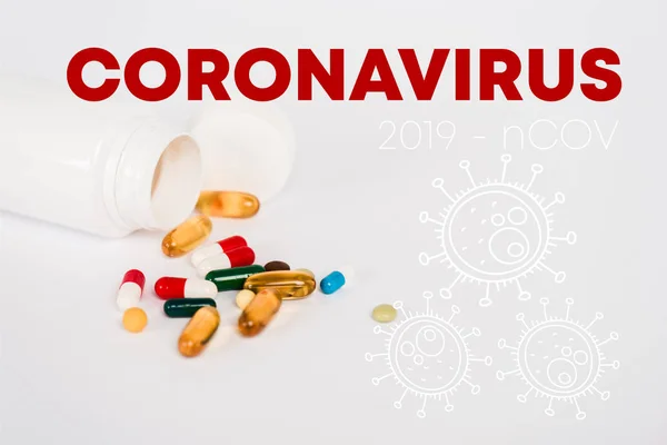 Bottle near colorful pills and coronavirus lettering on white — Stock Photo