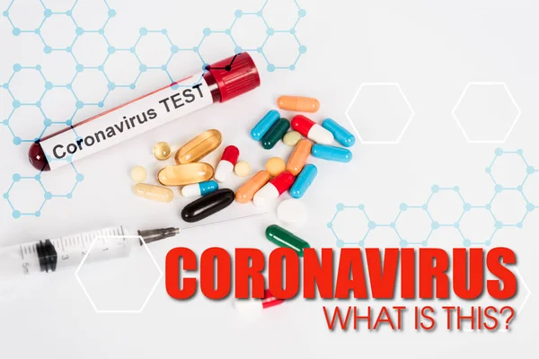 Píldoras de colores cerca de la muestra con la prueba de coronavirus, jeringa y coronavirus ¿qué es esta inscripción en blanco - foto de stock
