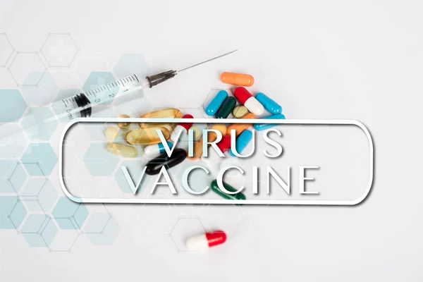 Pilules colorées près de la seringue et le vaccin contre le virus lettrage sur blanc — Photo de stock