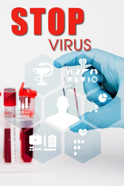 Cropped view of scientist holding glass bottle with liquid near test tubes and stop virus lettering on white — Stock Photo