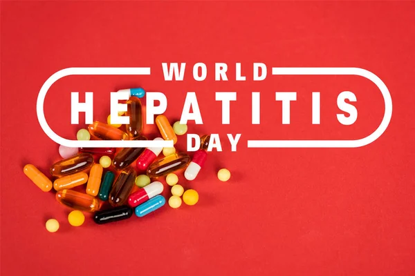 Colorful pills near world hepatitis day lettering on red — Stock Photo