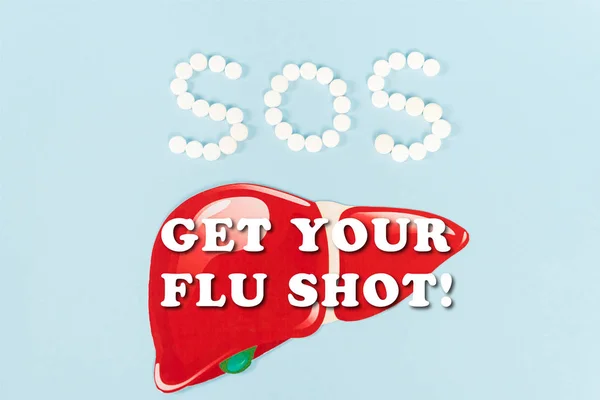 Vista superior del hígado dibujado cerca de sos y obtener sus letras de la vacuna contra la gripe en azul - foto de stock