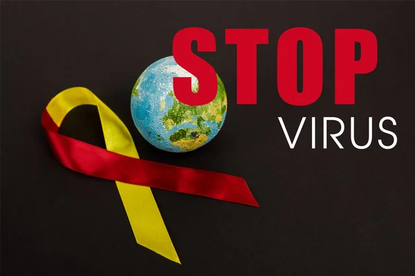 Nastro rosso e giallo vicino al globo e fermare il virus lettering su nero — Foto stock
